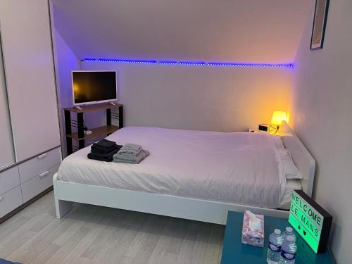 a bedroom with a white bed and a tv at Chambres dans maison familiale in Le Mans