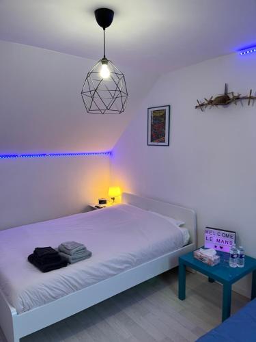 a bedroom with a white bed and a table at Chambres dans maison familiale in Le Mans