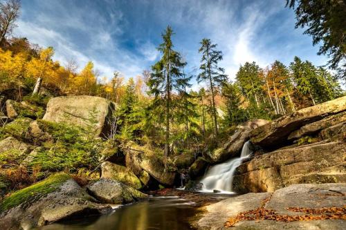 a waterfall in a forest with rocks and trees at Horský apartmán Stella in Janov nad Nisou