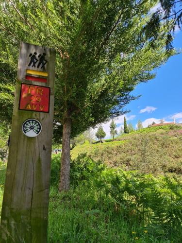 a wooden sign in the grass next to a tree at Casa Maria da Eira in Arcos de Valdevez