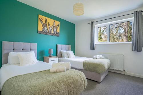 Duas camas num quarto com paredes azuis e uma janela em Raymond James Accommodation, sleeps up to 7, free parking, perfect for industries em Peterborough