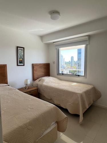 a hotel room with two beds and a window at Apartamento en Arenas del Mar, Punta del Este in Punta del Este
