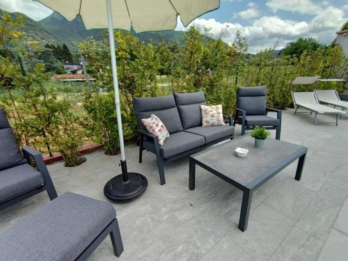 patio con divani, tavolo e ombrellone di La Pitorina Holidayhome a Camaiore