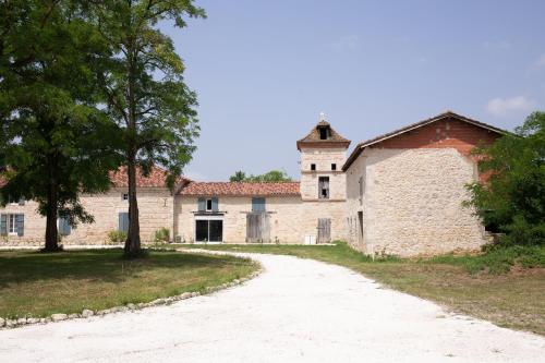 un vieux bâtiment en pierre avec un arbre et un chemin de terre dans l'établissement Le Clos Saint-Jean - Chambre d'hôte Scarlett, à Saint-Jean-de-Thurac