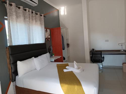 a bedroom with a white bed with a white shoe on it at Shalakwe Hills-Inn Guesthouse Kasane in Kasane
