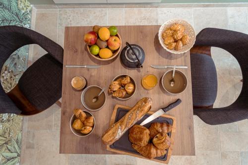 a table with various types of bread and fruit on it at Les clés d'à côté - maison d'hôtes de charme près de Rouen in Sotteville-lès-Rouen