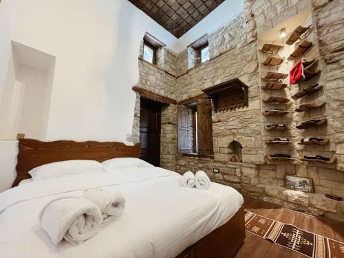 a bedroom with a large bed and a stone wall at Tradita e Beratit in Berat