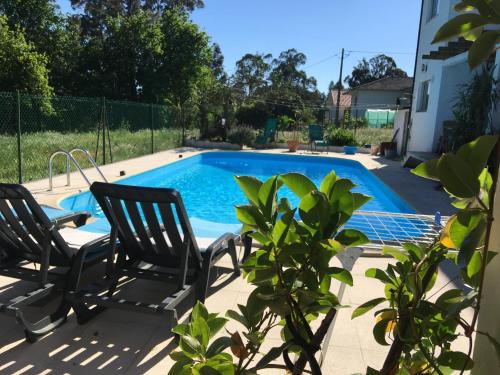 a swimming pool with two chairs next to it at Sossego na cidade in Viseu