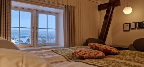 a bedroom with a bed with pillows and a large window at Vertshuset Røros in Røros