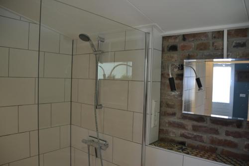 een badkamer met een douche en een spiegel bij het Bakhuis in Hoensbroek