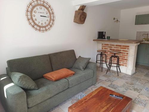a living room with a couch and a clock on the wall at Gîte Le Tico in Cheverny