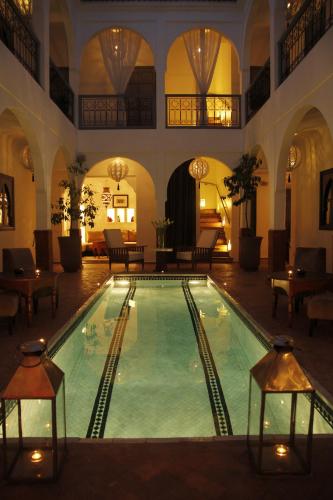 a large swimming pool in a building with tables and chairs at Riad Utopia Suites And Spa in Marrakesh