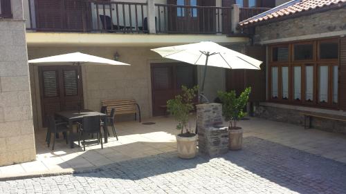 a patio with two umbrellas and a table and chairs at Moleiro de Bacal in Baçal