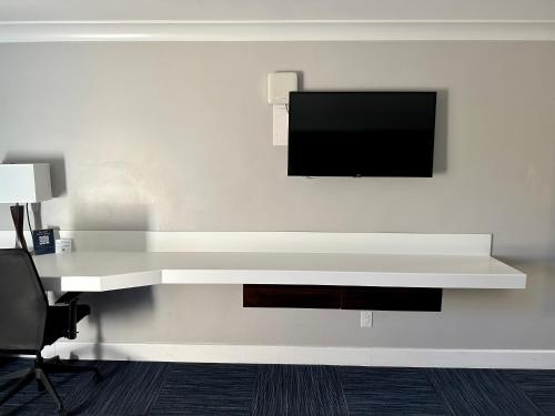 a white desk with a television on a wall at The Pacific Inn in Seal Beach