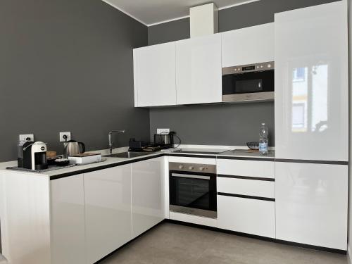 una cucina bianca con armadietti e elettrodomestici bianchi di NONSOLOMARE Wifi aria condizionata ascensore a Sanremo