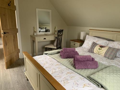 een slaapkamer met een bed met paarse kussens en een bureau bij Birchwood View in Aboyne