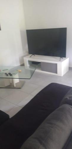 un soggiorno con una TV e un tavolo di vetro di VILLA JAGUAR a Le Gosier