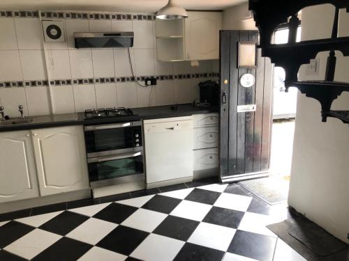 una cucina con pavimento a scacchi in bianco e nero di The Coach House Cottage, Bridge House Mews a Newbold