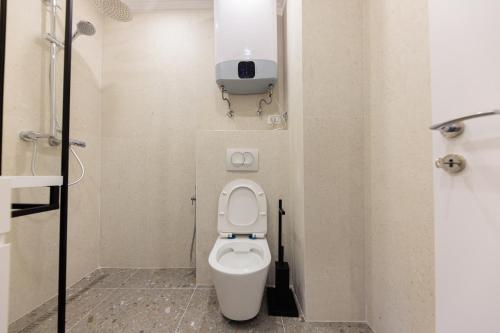 a small bathroom with a toilet with a tv on the wall at One-bedroom rooftop skyline central hidden gem in Tirana in Tirana