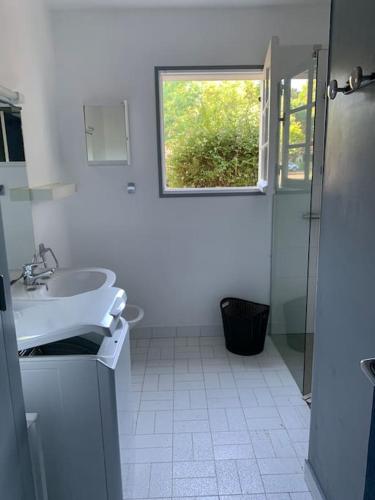 une salle de bain blanche avec un lavabo et une fenêtre dans l'établissement Belle maison familiale indépendante avec jardin., à Vielle-Saint-Girons