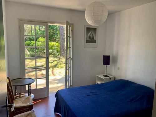 - une chambre avec un lit bleu et une porte coulissante en verre dans l'établissement Belle maison familiale indépendante avec jardin., à Vielle-Saint-Girons