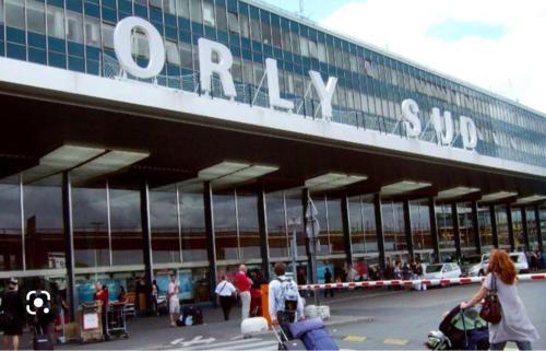 un gruppo di persone che camminano fuori da un aeroporto di Jolie F2 à 5mn de l'aéroport d'Orly a Paray-Vieille-Poste