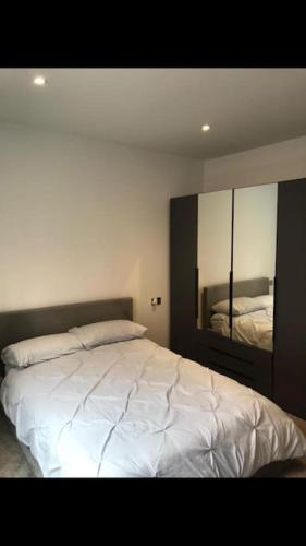 a bedroom with a white bed and a mirror at Stylish Camberley Apartment in Camberley