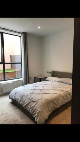 a bedroom with a bed and a large window at Stylish Camberley Apartment in Camberley