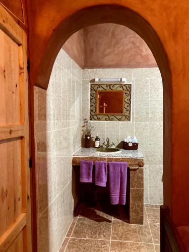 a bathroom with a sink and purple towels at Riad Imuhar in Mhamid