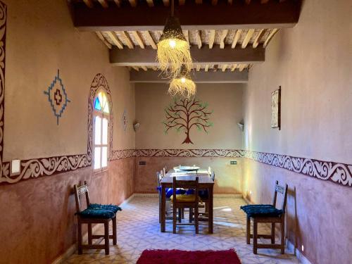 ein Esszimmer mit einem Tisch, Stühlen und einem Kronleuchter in der Unterkunft Riad Imuhar in M’hamid El Ghizlane