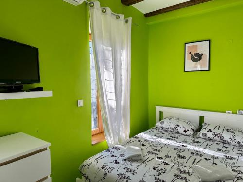 a green bedroom with a bed and a television at Das Hostel Rijeka in Rijeka
