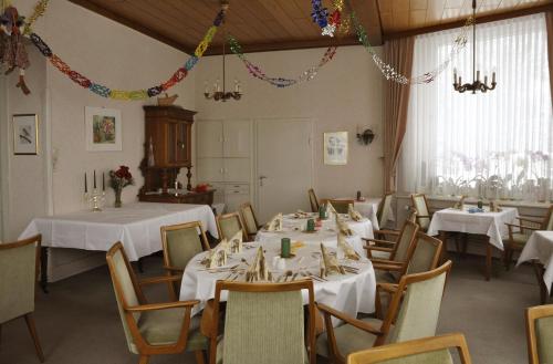 uma sala de jantar com mesas e cadeiras brancas em Haus Dümling em Braunlage