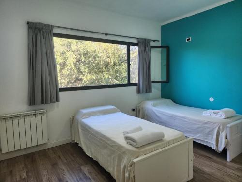 twee bedden in een kamer met een raam bij El Aguaribay casa de montaña in Cortaderas