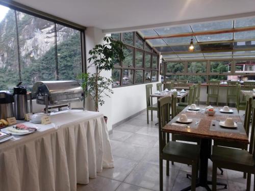 a restaurant with tables and chairs and windows at Hotel Pucara Machupicchu in Machu Picchu