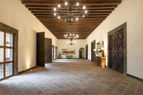 un grand couloir avec un plafond orné d'un lustre dans l'établissement Hotel Hacienda la Venta, à San Juan del Río