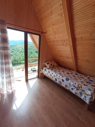 a bed in a room with a large window at Căsuțele din Zăbran in Gornenţi