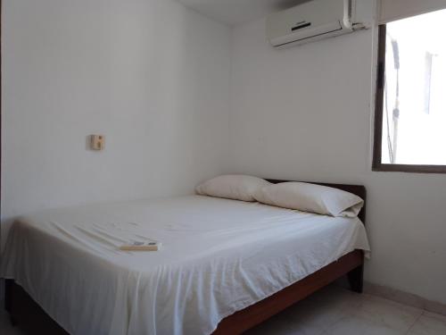 uma cama com lençóis brancos e almofadas num quarto em Apartamento frente al mar em Rodadero