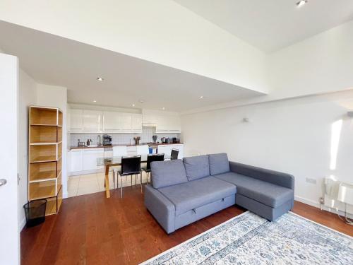 a living room with a couch and a kitchen at Portobello Dock - Canal Views with Garden in London