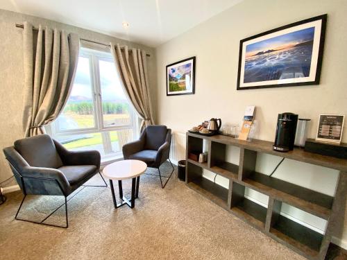 a living room with two chairs and a desk and a window at Mingarry Park in Acharacle