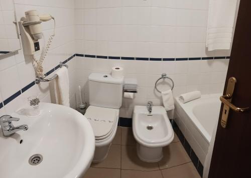 La salle de bains est pourvue d'un lavabo, de toilettes et d'une baignoire. dans l'établissement Hotel Insular, à Ponta Delgada