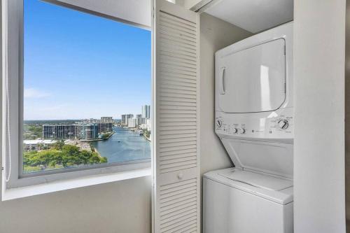 Un lavadero con lavadora y ventana. en Luxury condo with ocean view 4Bedrooms 3Bathrooms, en Hallandale Beach