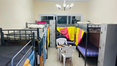 a room with two bunk beds and a table and chairs at Dubai Star Hostel in Dubai