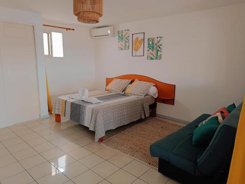 1 dormitorio con 1 cama y 1 sofá en Cibuqueira numéro 5, Appartement en centre ville,vue sur mer, plage à pied en Le Moule