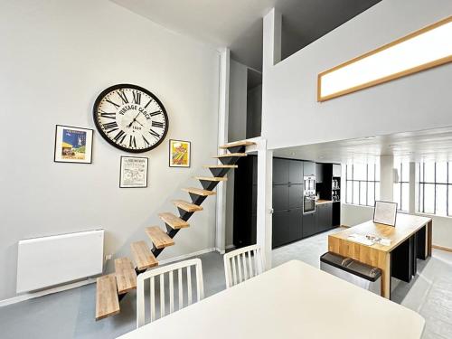 - un salon avec une horloge sur le mur et des escaliers dans l'établissement "Silk & Suites" City Center, à Saint-Étienne