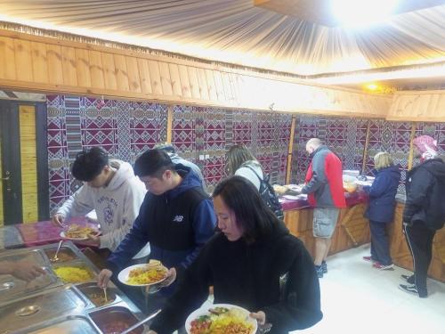 a group of people eating food at a buffet at orbit camp 2 in Wadi Rum