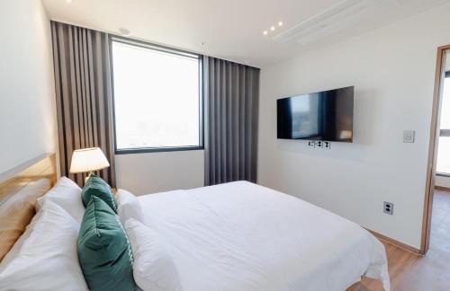 a white bedroom with a bed and a tv at Hotel Arari in Jeonju