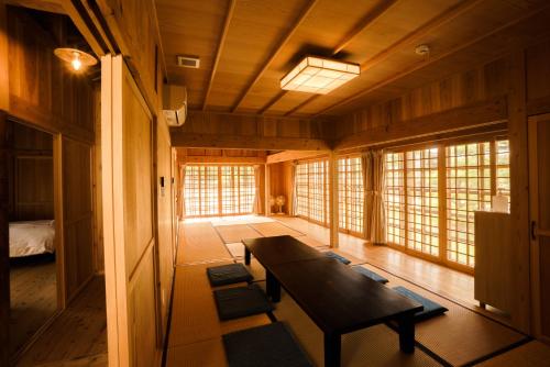 a living room with a wooden table and windows at かたあきの里 in Miyako Island
