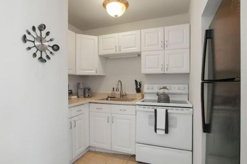 uma cozinha com armários brancos, um lavatório e um frigorífico em Sleek Gold Coast Studio Apartment - Chestnut 19E em Chicago