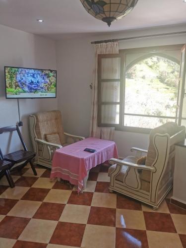 a living room with a table and chairs and a window at Cascadas al Onsar Chefchauen in Chefchaouen