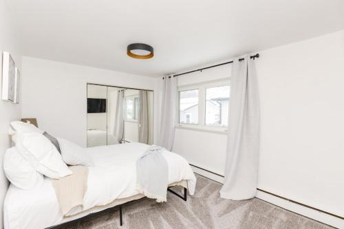 ein weißes Schlafzimmer mit einem Bett und einem Spiegel in der Unterkunft NEW Remodeled Townhome in Central Fargo in Fargo